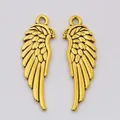 Detailed macro view of golden alloy wing pendants with textured feathers for DIY jewelry - Antique Gold