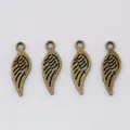 Detailed view of four vintage bronze alloy wing pendants with intricate feather textures - Antique Bronze