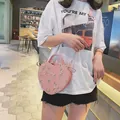 Sac bandoulière cœur rose avec broderie florale et chaîne dorée porté par un modèle - Rose