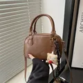 Bolso bowling retro marrón con asas y colgante de peluche en un ambiente cálido de interior - Con Colgante / Marrón