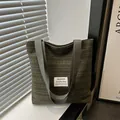 Modern dark green striped canvas tote bag with wide straps and minimalist design labels - Green