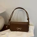 Bolso bandolera de cuero marrón con cierre de lazo dorado y detalle de correa anudada - Marrón