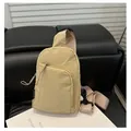 Bolso bandolera de nailon beige con correa marrón ajustable sobre superficie de cuero - Caqui