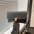 Elegante borsa a mano nera testurizzata con chiusura geometrica dorata e cinturino da polso - Nero