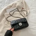 Klassieke zwarte gewatteerde crossbodytas met zilveren ketting op een beige blazer - Zwart