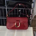 Bolso vintage de charol color burdeos con hebilla dorada sobre un libro abierto - Burdeos