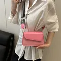 Pink crossbody bag with checkerboard strap and mixed texture panels shown on a model - Pink