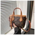 Borsa a secchiello marrone con motivo vintage e bordi rossi, tenuta in mano - Stampa Lettere Fiori Stelle (Hor)