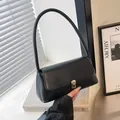 Bolso de hombro minimalista en cuero sintético negro con cierre dorado en estudio moderno - Negro