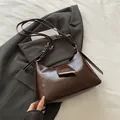 Minimalistische donkerbruine hobo-tas met glanzende afwerking en gouden gesp op pak - Koffie