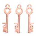 Detailed macro view of three rose gold alloy key pendants with heart and love engravings - Rose Gold