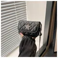 Quilted black chain crossbody bag with silver star buckle held by hand in sunlight - Black