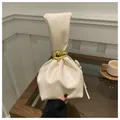 Chic beige pleated bucket bag with a distinctive gold bean-shaped metal handle detail - White