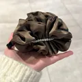Détail d'une pince banane en satin plissé marron avec perles élégantes pour cheveux - Marron