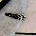 Detail van zilveren strass bloem haarklem met zwart-wit stippenpatroon op stof - Zwarte Stippen Bloem Stijl
