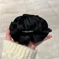 Détail d'un chouchou noir à volants orné de perles blanches élégantes en satin doux - Noir