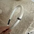 Elegant white satin padded headband featuring a sparkling dark rhinestone buckle detail - Off-white