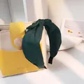 Detail eines dunkelgrünen Satin-Haarreifs mit Knoten neben einer modernen Handtasche - Dunkelgrün