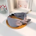 Eleganter grauer Stoff-Haarreif mit Knotendesign auf einem minimalistischen Holztablett - Grau