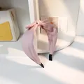 Pink fabric headband with knot bow detail on display stand with natural lighting - Pink