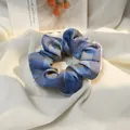 Détail d'un chouchou à carreaux bleu et marron avec une texture de tissu doux et plissé - Plaid Bleu Clair