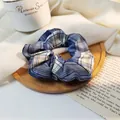 Vue détaillée d'un chouchou à carreaux bleu marine avec dentelle sur un plateau en bois - Carreaux Marine