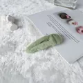 Elegant light green faux fur hair clip on white plush background for autumn winter - Green
