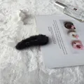 Elegante pinza de pelo de piel sintética negra sobre un fondo estético minimalista - Negro