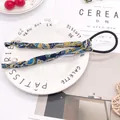 Elastic hair scrunchie with blue paisley ribbons and white pearl pendants on a ceramic plate - Navy Totem
