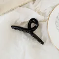 Elegant large black glossy hair claw clip with cross design on white textured paper - Black