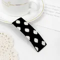 Detailed view of a black and white polka dot fabric hair clip on a decorative background - White Dots Black Clip