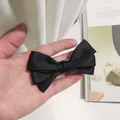Barrette à cheveux à nœud multicouche en satin noir tenue à la main, style épuré - Noir