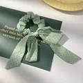 Detailopname van een lichtgroene scrunchie met stippen en strik op een kaart - Groen