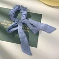 Detailopname van blauwe scrunchie met stippen, strik en lange soepele linten - Blauw