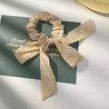 Detailopname van beige haarelastiek met gele stippen en strik op een groene kaart - Vleesroze