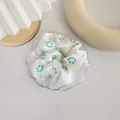 Close-up of white satin scrunchie with green smiley faces on a glass tray - White Cute Smiley