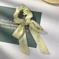 Detail van lichtgele haarwokkel met groene stippen en strik op een sierkaart - Geel