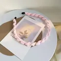 Detalle de una diadema de tela rosa claro retorcida con estructura de alambre dorado - Rosa