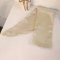 Detail of elegant champagne satin hair scarf ribbon with smooth texture and silk finish - Beige