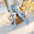 Dettaglio dell'elastico in raso azzurro con grande fiocco su vassoio in legno - Azzurro