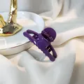 Detail of glossy dark purple hair claw clip with metal spring on elegant white fabric - Purple