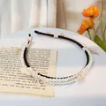Detail van een elegante parel hoofdband met crème satijnen strikken en parels - Beige