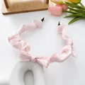 Pink satin pleated headband featuring a bow and soft scrunchie texture for women - Pink