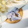 Primer plano de un coletero de satén violeta claro sobre una bandeja de madera rústica - Gris claro