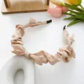 Elegant pleated satin bow headband in soft nude pink finish with silky texture - Champagne