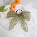 Detail of olive green lace bow hair tie with elegant artistic letter prints on soft fabric - Green