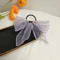 Detail of a purple mesh lace bow hair tie with silver scripts in a golden tray - Purple