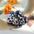 Detail of blue and white checkered fabric scrunchie on an artistic cream stand - Navy Blue