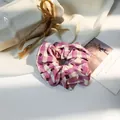 Close-up of purple and beige gingham fabric scrunchie in a cozy aesthetic setting - Pink