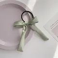 Elegant light green satin bow hair tie with long ribbon on a stylish ceramic plate - Green